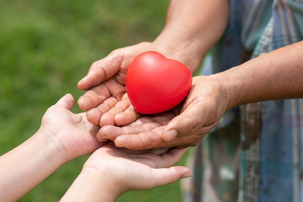 Trasplante de corazón - un hombre mayor dando un corazón de platico a un niño