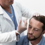 Implante capilar -especialista aplicando un tratamiento capilar en inyecciones en la línea del cabello de un paciente