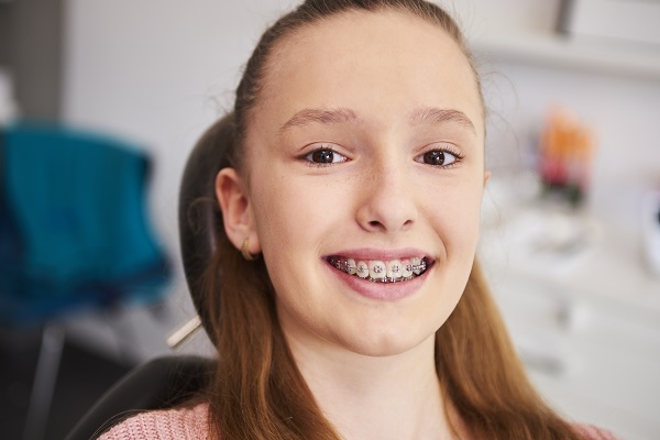 joven mujer en clínica dental, sonríe después de la revisión de sus brackets, algo que influye en el precio de este tratamiento