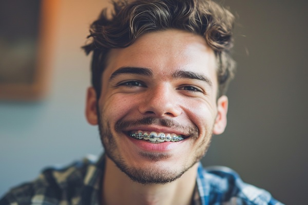 joven adulto, con camisa de cuadros, muestra su correctores, como tratamiento para corregir sus dientes