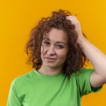 cuero cabelludo inflamado - mujer con el Cuero cabelludo inflamado se toma el cabello con incomodidad