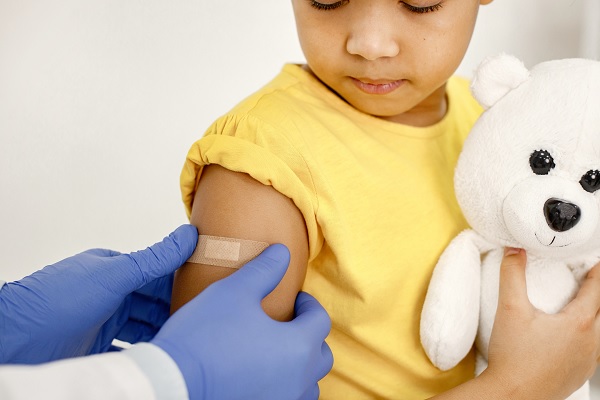 especialista colocando una curita en el brazo de niño, luego de vacunarlo contra el sarampión 