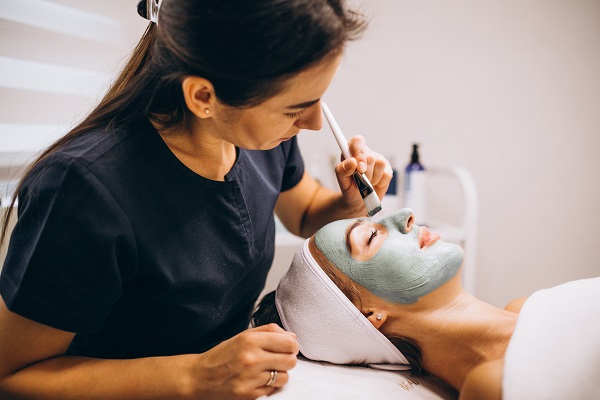 especialista le aplica una mascarilla a una paciente, para ayudar con la piel grasa