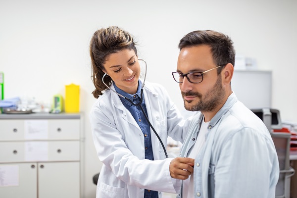 en una clínica de cardiología, una cardióloga examina con estetoscopio el corazón de paciente masculino