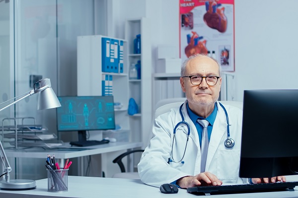 en una clínica de cardiología, un cardiologo con evidente experiencia, lo cual es una buena señal a la hora de escoger la mejor clínica; esta sentado en su escritorio,
