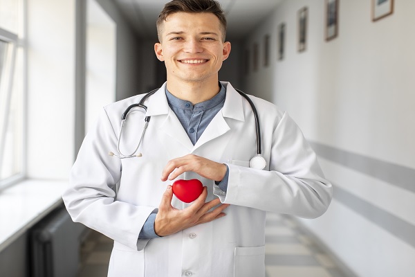 un joven especialista posa con el símbolo de un corazón rojo en la mano 