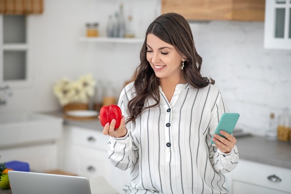 mujer sostiene un pimiento rojo, como simbolo de una dieta saludable que ayuda a la prevención de enfermedades cardiacas
