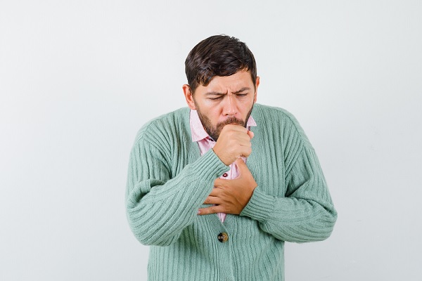 historia natural de la tosferina, hombre adulto con sueter verde, con un ataque de tos fuerte