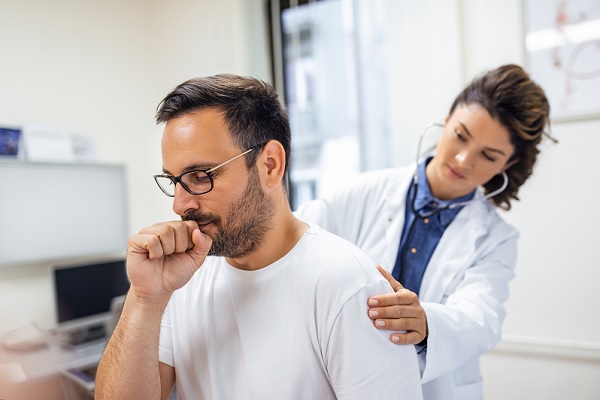 un doctora escucha los pulmones de paciente con tos