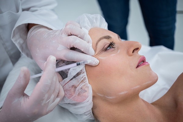 Mujer recibiendo inyección para un tratamiento facial en arrugas por profesional médico