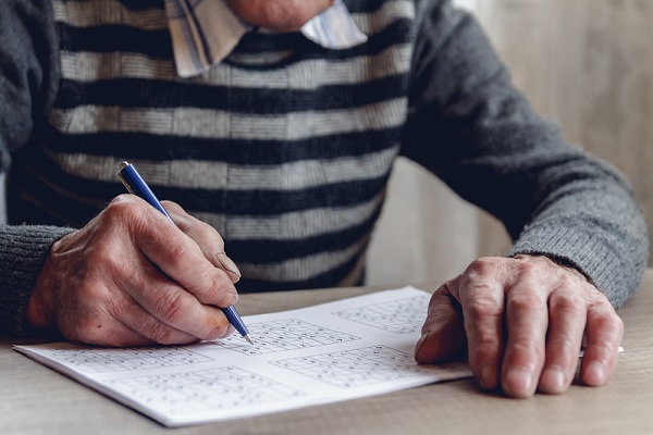 un anciano resuelve un sudoku para mantener su mente activo