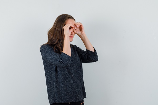 cataratas en los ojos, una mujer trata de enfocar su vista con sus manos alrededor de sus ojos