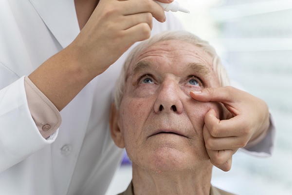 un medico le pone gotas en los globos oculares a un anciano