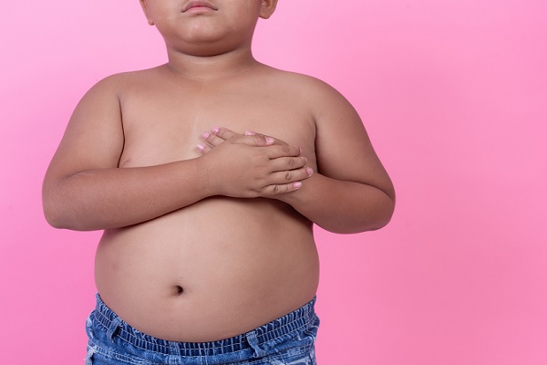 síndrome metabólico en niños, un niño obeso con sus manos en el lado izquierdo de su pecho