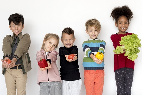 unos niños sostienen verduras que se necesitan para un dieta saludable y evitar este problema