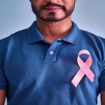 cáncer de mama en hombres - hombre de camisa azul con una cinta rosa en el pecho, que simboliza el cáncer de mama