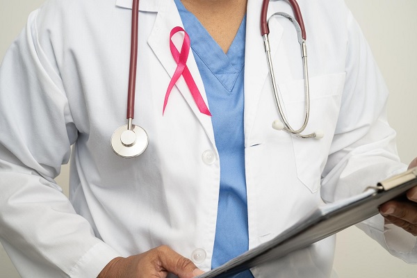 cáncer de mama en hombres - doctor con cinta rosa en su bata, sostiene una tabla con informes médicos 