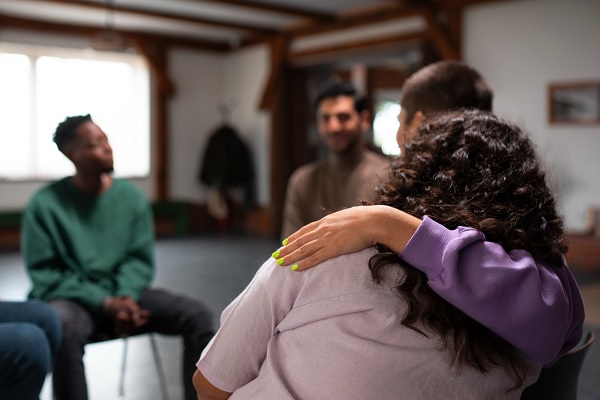 varias personas reunidas en un grupo de apoyo, lo que contribuye a reducir el impacto psicológico de la enfermedad en las personas