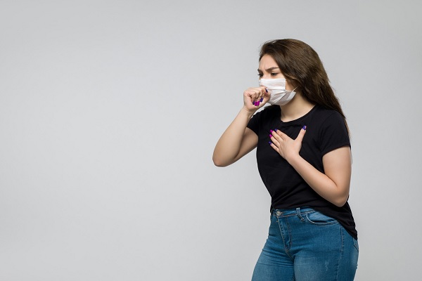 enfermedades más comunes en México - una mujer con influenza usa mascarilla mientras tose